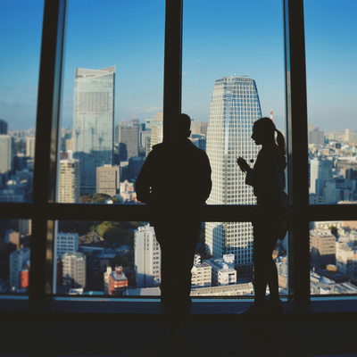 Silhouettes of two people talking in front of a city skyline